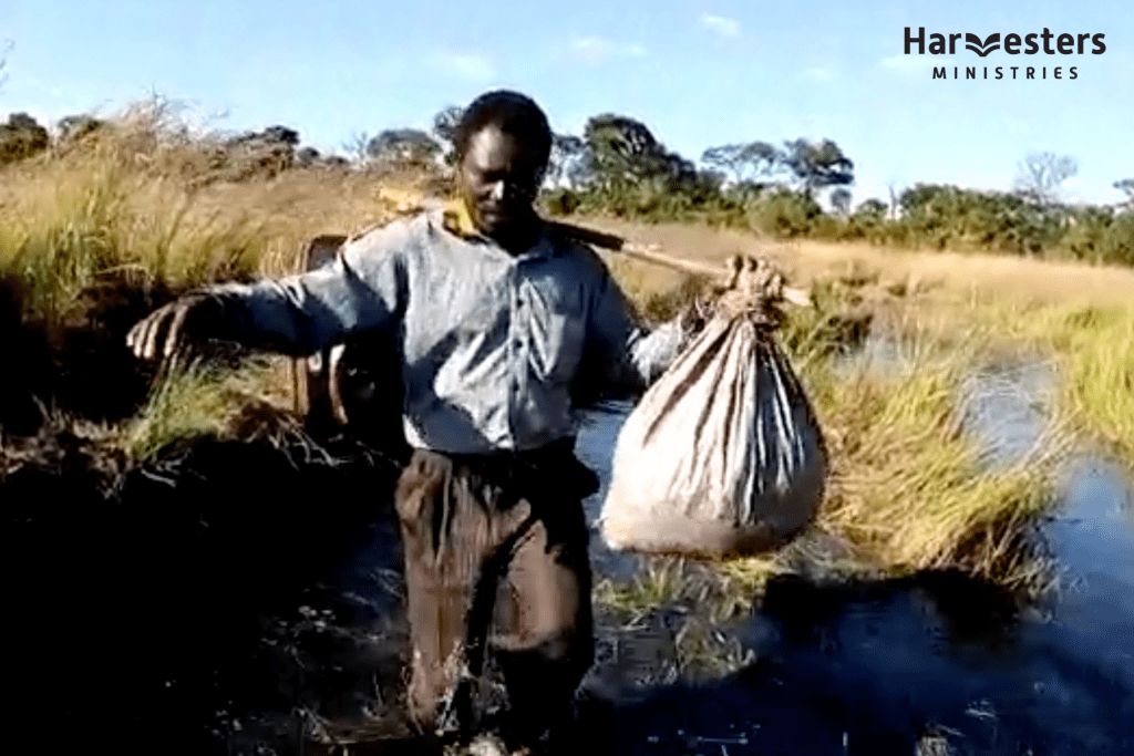 Pastor Peter wading through flood waters in Angola. Harvesters Ministries