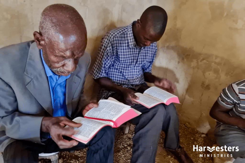 Zambia bible delivery - men reading. Harvesters Ministries