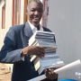 Man smiling with stack of Bibles